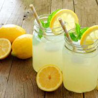 Limonata fatta in casa in due bicchieri a calice, con fettine di limone a decorare.