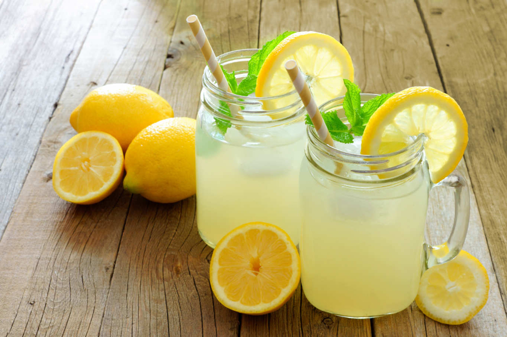 Limonata fatta in casa in due bicchieri a calice, con fettine di limone a decorare.