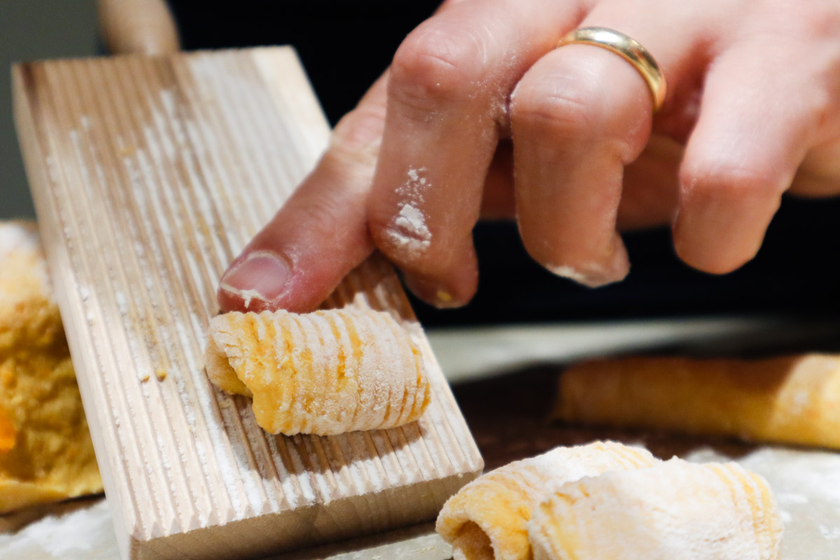 Realizzazione dei gnocchi di zucca senza patate utilizzando una tavolozza per gnocchi. Impasto premuto sulla tavolozza.