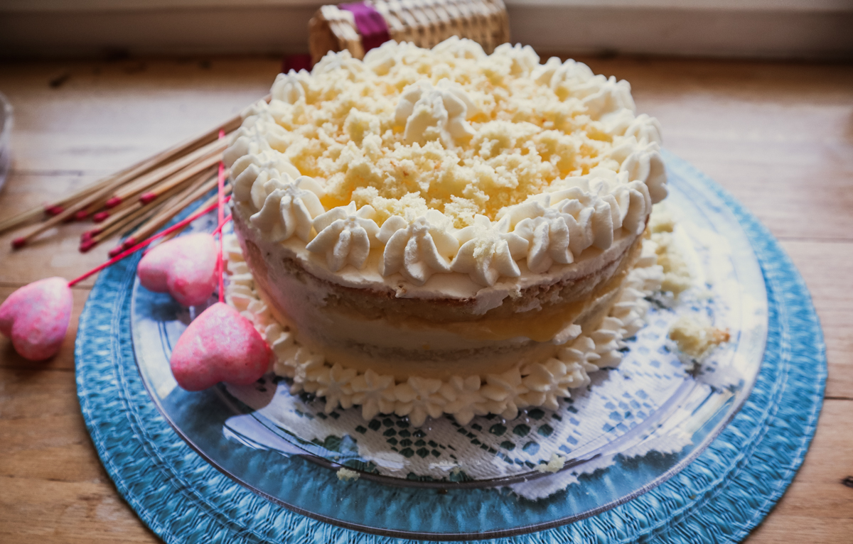 Primo piano della torta mimola con crema chantilly al limone su vassoio di vetro.