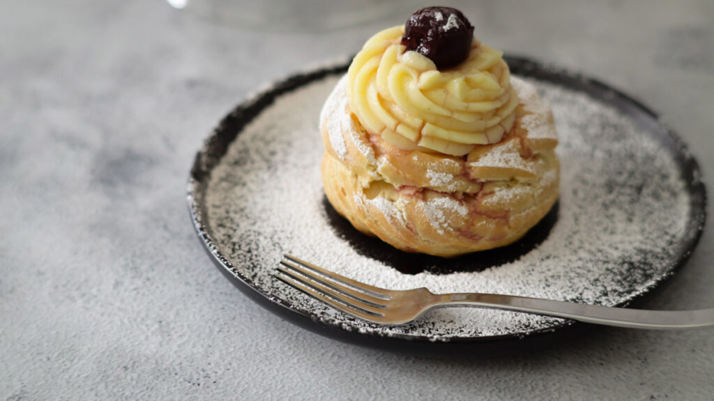 Zeppole di San giuseppe su piatto spolverata di zucchero a velo.