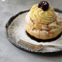 Zeppole di San giuseppe su piatto spolverata di zucchero a velo.