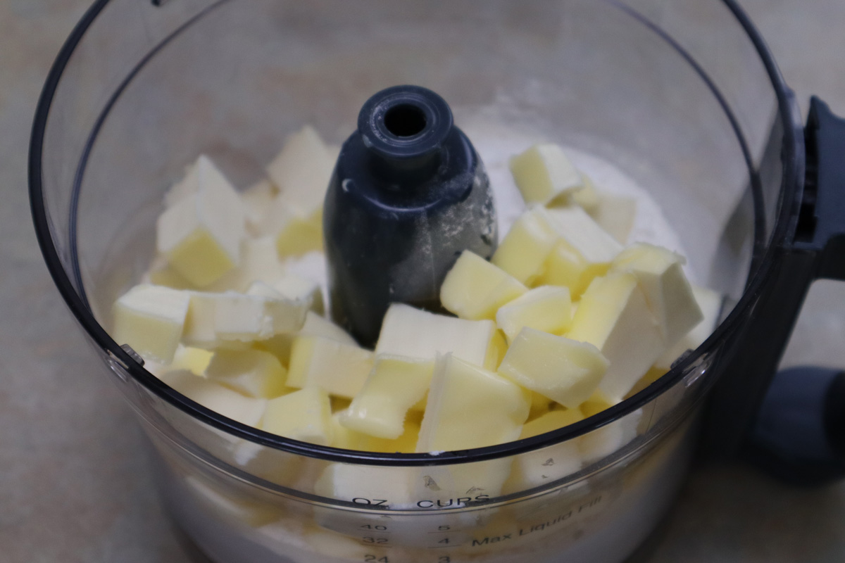 Impasto per la pasta brisè pronto nel robottino. Zucchero, sale, burro e farina pronti ad essere tritati.