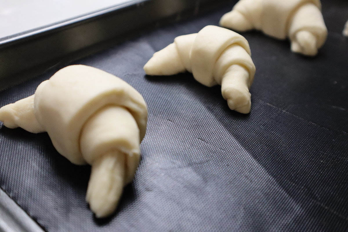 Realizzati i cornetti salati disponeteli su una leccarda foderata da carta forno oppure con un tappetino di silicone adatto alla cottura in forno di alimenti.